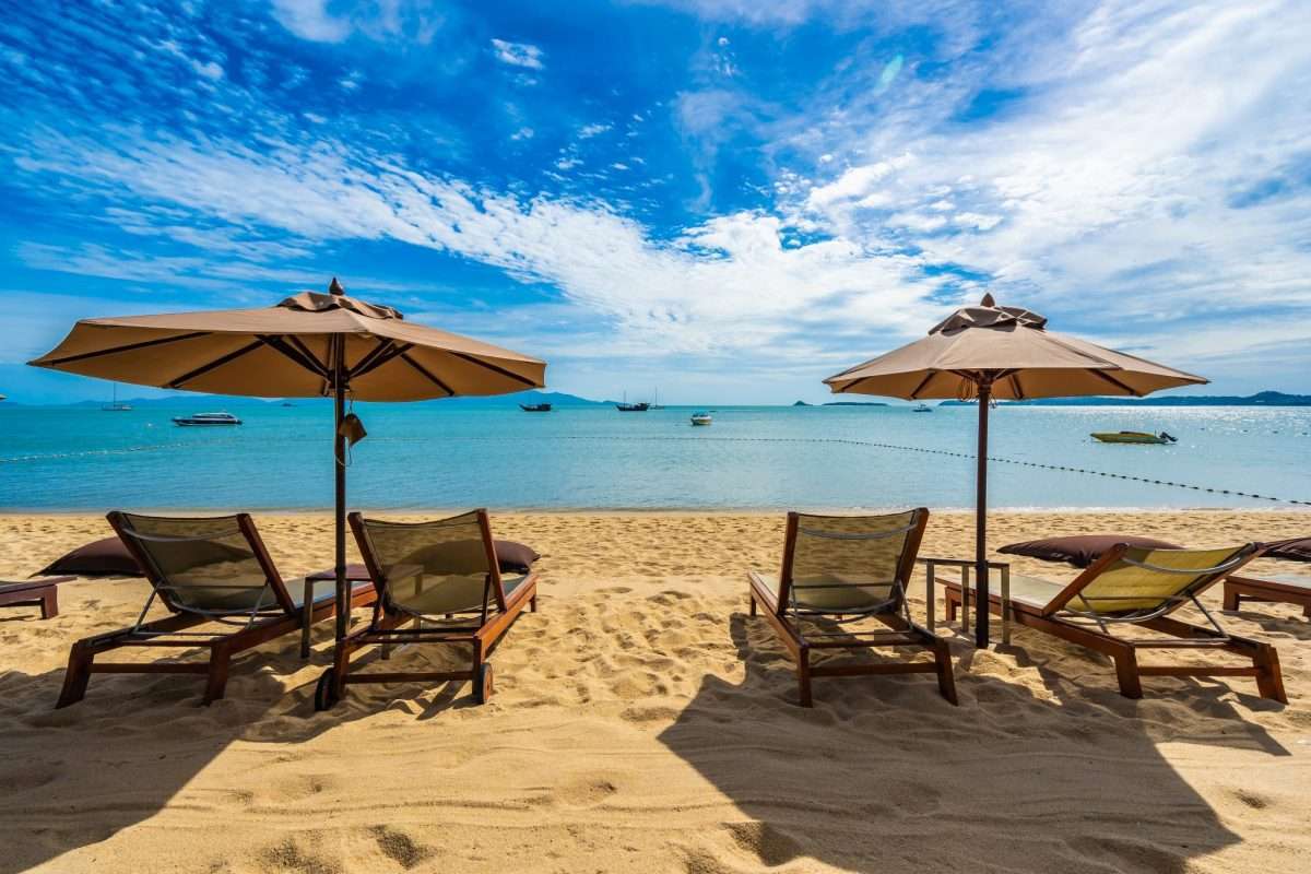 beautiful tropical beach sea ocean with coconut palm tree umbrella chair blue sky scaled e1648481367645